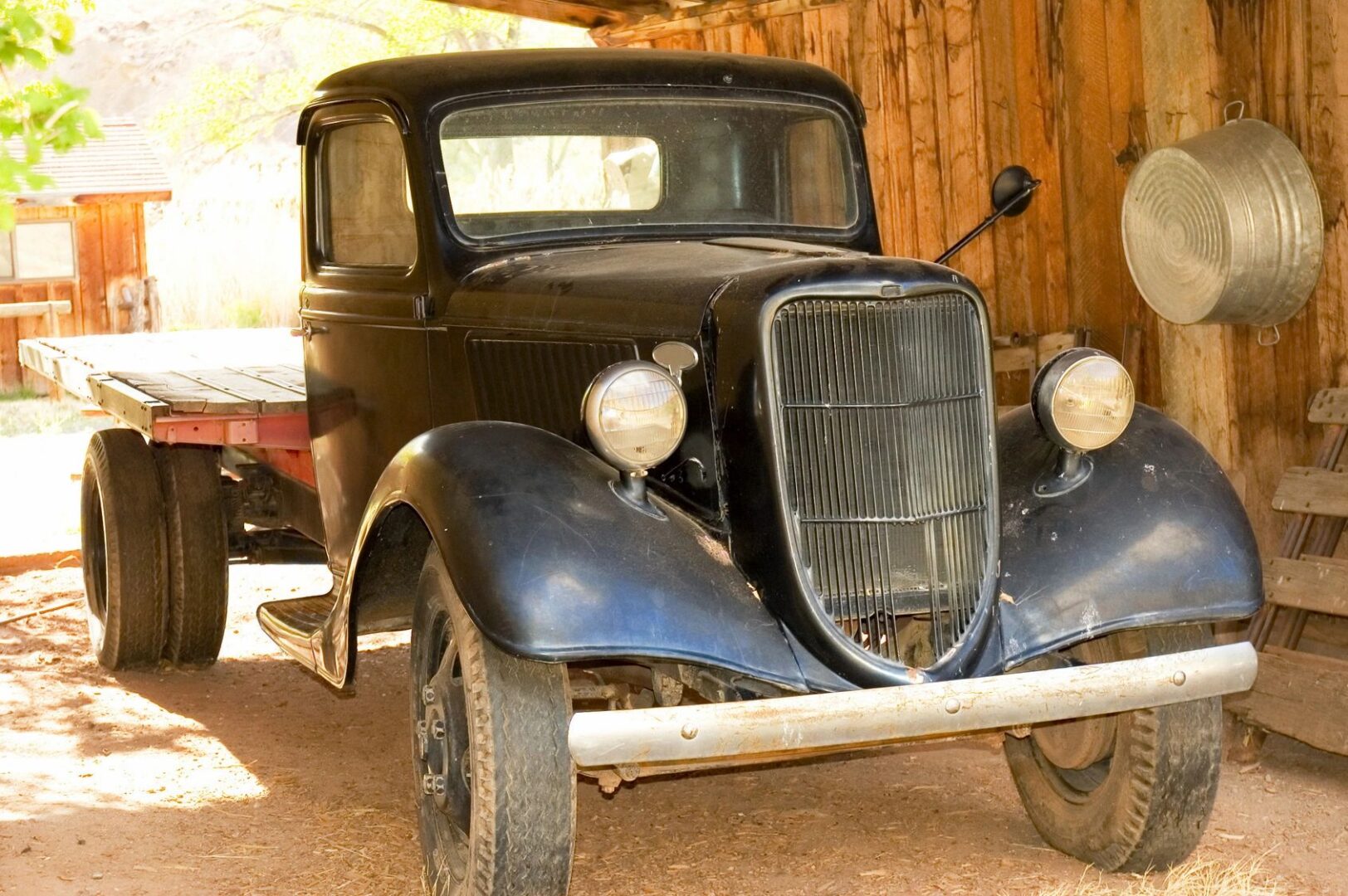 A black truck parked in front of a wooden building.